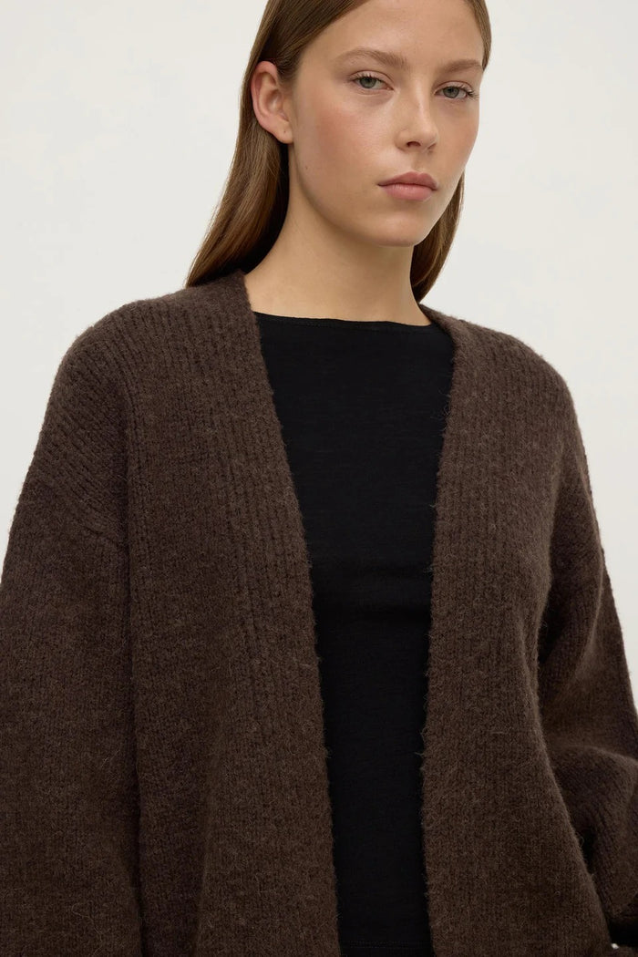 Woman wearing a brown cardigan over a black top on a white background