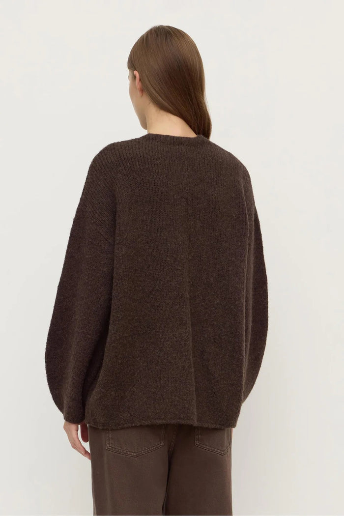 Person wearing a brown sweater and pants on a white background