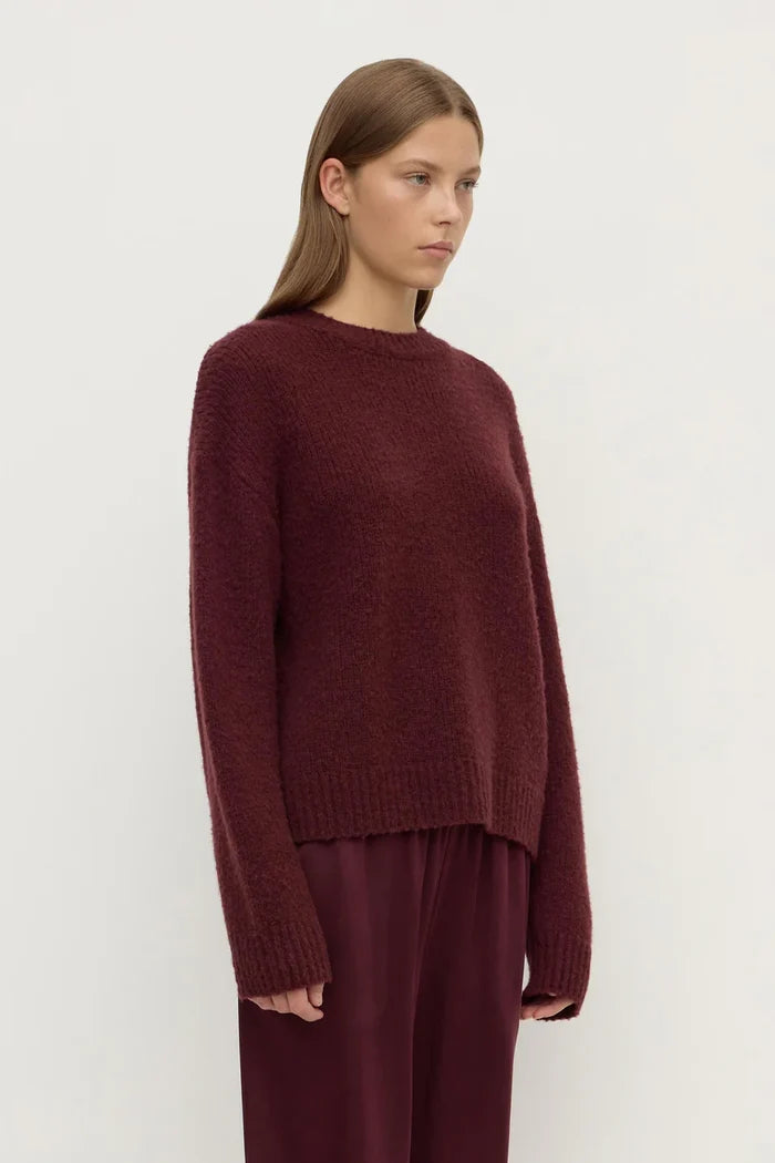 Woman wearing a burgundy sweater and pants on a white background