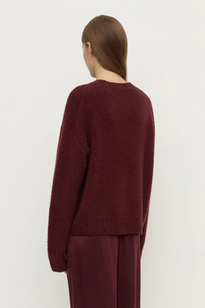 Person wearing a burgundy sweater and pants on a white background