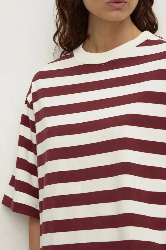 A close-up of a person wearing an oversized short-sleeve crewneck t-shirt with horizontal burgundy and off-white stripes.