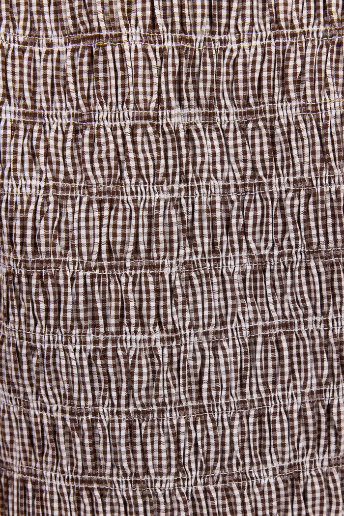 Close-up of a brown and white gingham fabric with horizontal smocked or gathered stitching.
