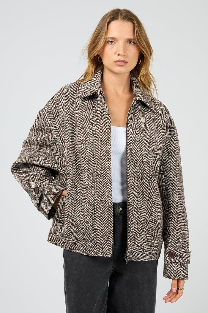 Woman wearing a brown patterned jacket on a light gray background