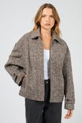 Woman wearing a brown patterned jacket on a light gray background