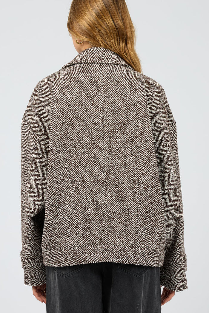 Person wearing a textured brown jacket on a plain background
