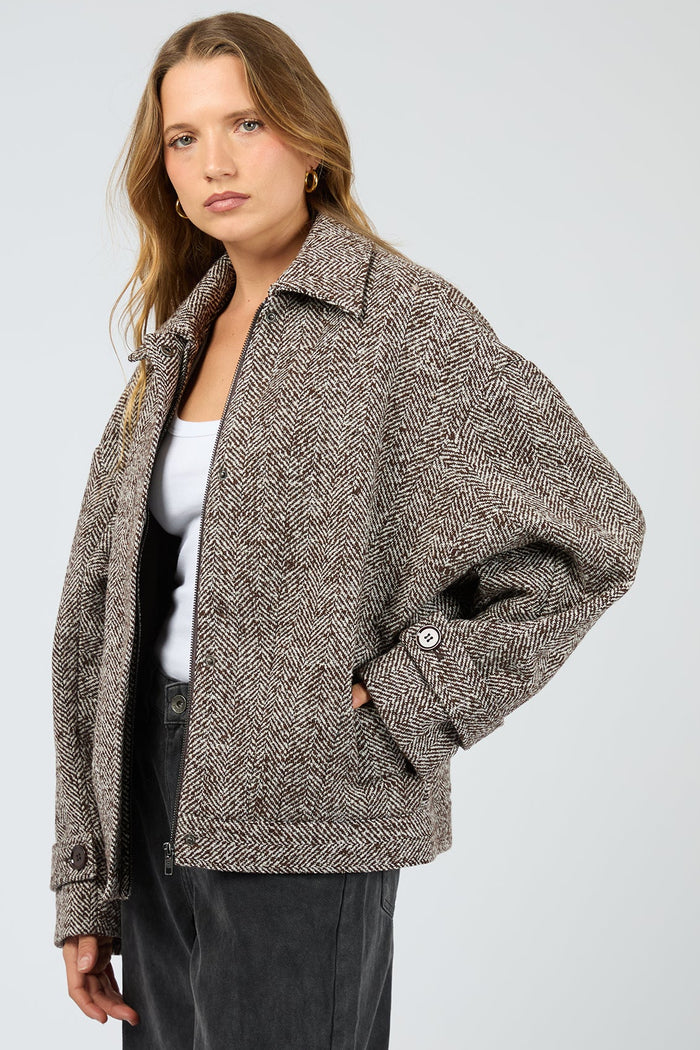 Woman wearing a textured brown jacket on a white background