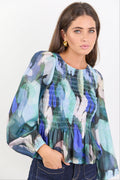 Woman wearing a colorful floral blouse against a white background