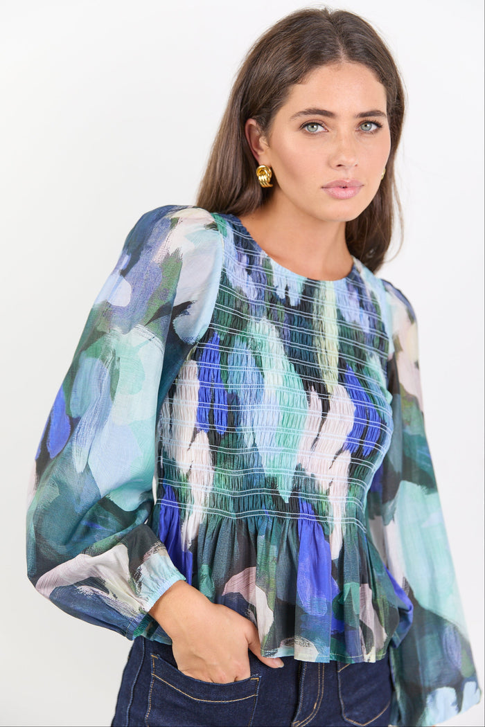 Woman wearing a colorful floral blouse against a white background