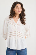 Woman wearing a white blouse with lace details and blue jeans on a white background
