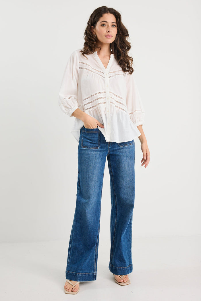 Woman wearing a white blouse and blue jeans on a white background