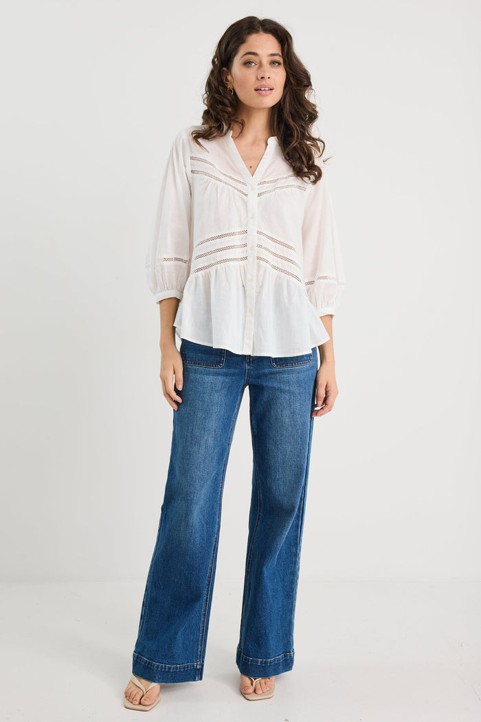 Woman wearing a white blouse and blue jeans on a white background