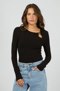 Woman wearing a black long-sleeve top with a cutout design and light blue jeans on a gray background