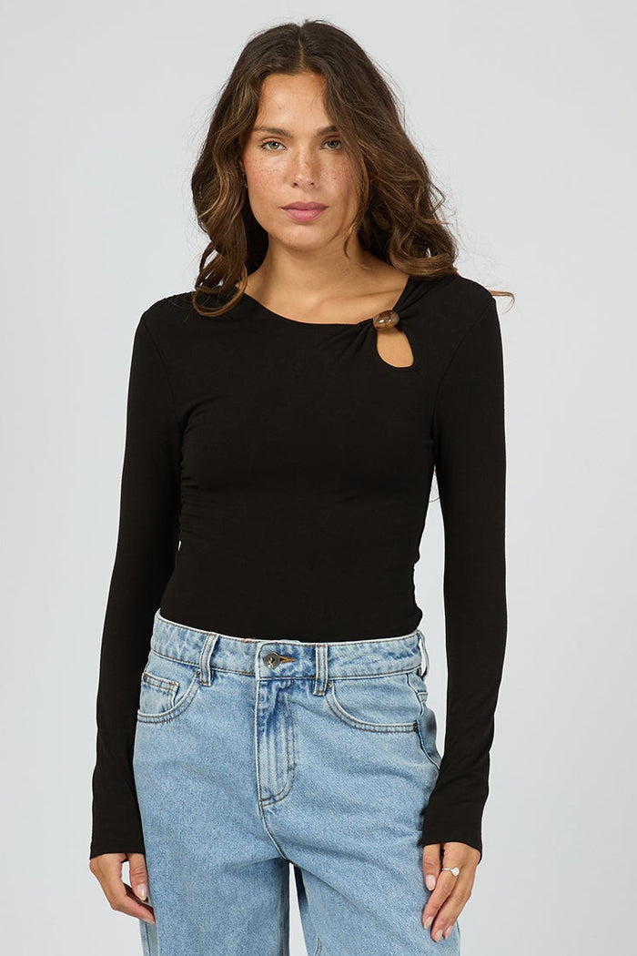 Woman wearing a black long-sleeve top and light blue jeans on a white background