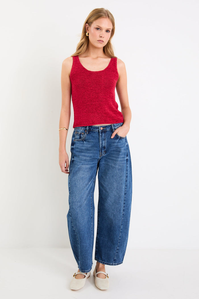woman wearing a red knit top and blue jeans