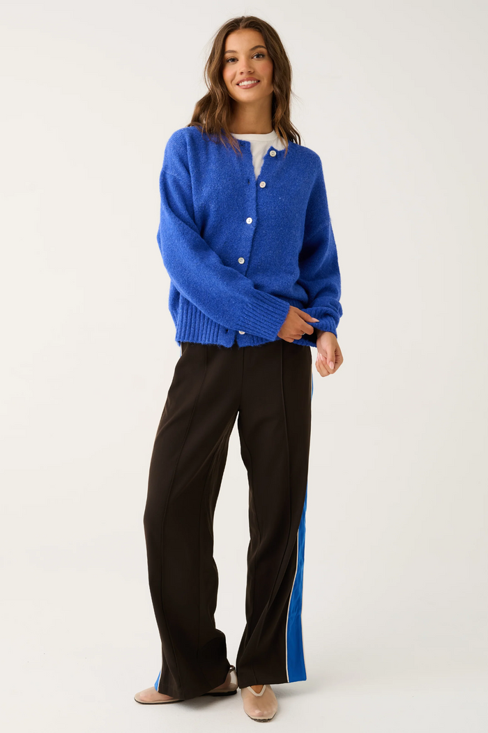 Woman wearing a blue cardigan and black pants with a white background
