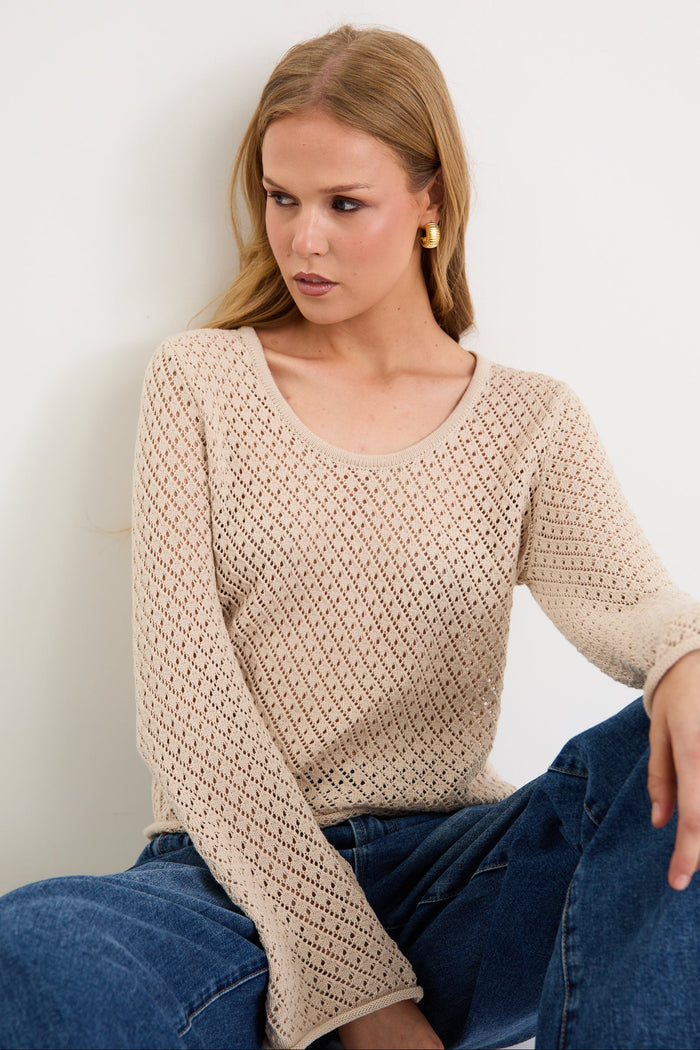 Woman wearing a light crochet knit and blue jeans