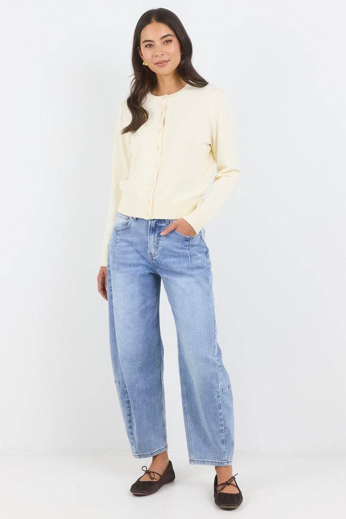 Woman wearing a light-colored top and blue jeans on a white background