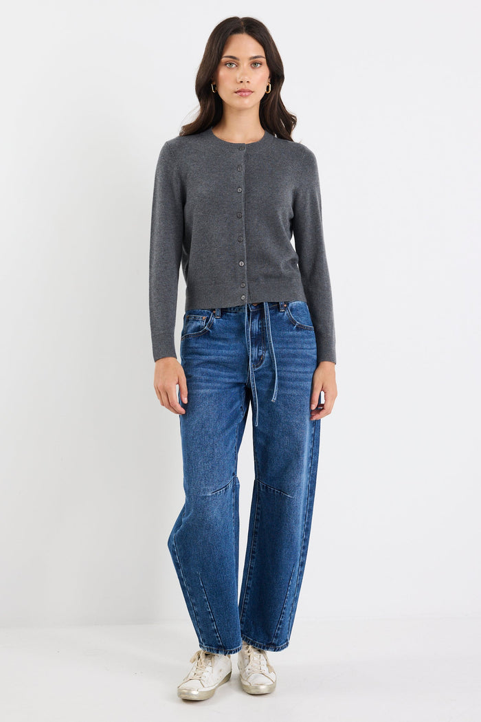 Woman wearing a gray cardigan and blue jeans on a white background