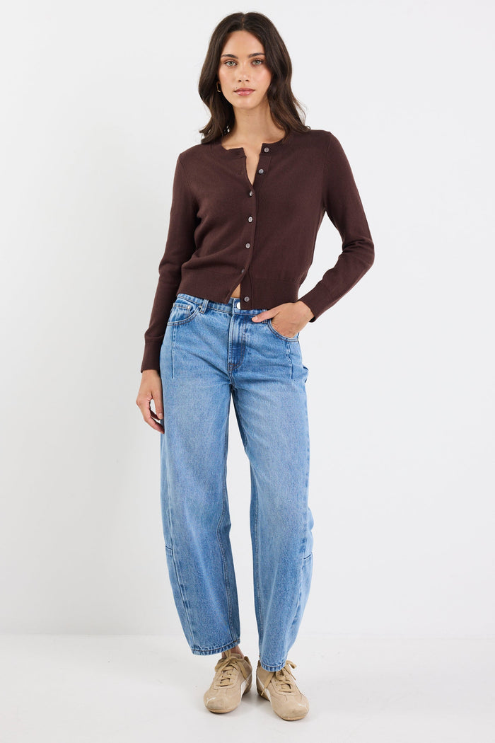 Woman wearing a brown button-up shirt and blue jeans on a white background