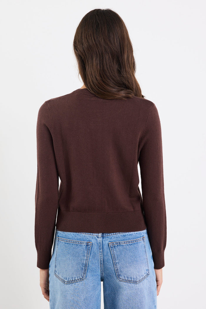 Person wearing a brown long-sleeve top and blue jeans on a white 
background
col_pattern