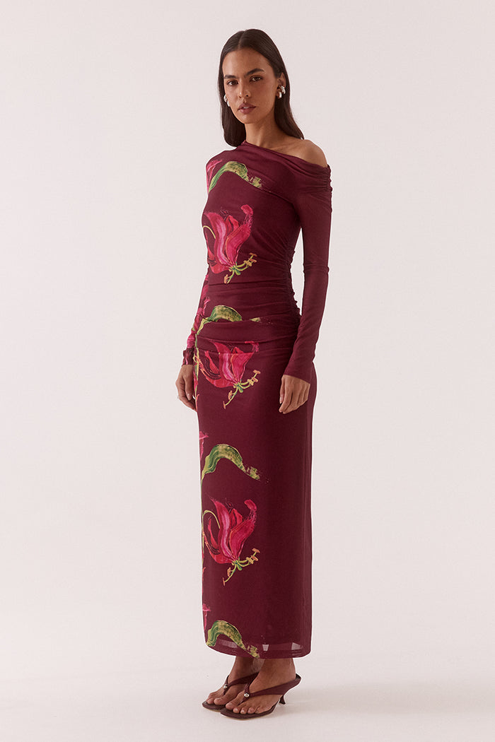 Woman wearing a burgundy dress with floral patterns on a white background