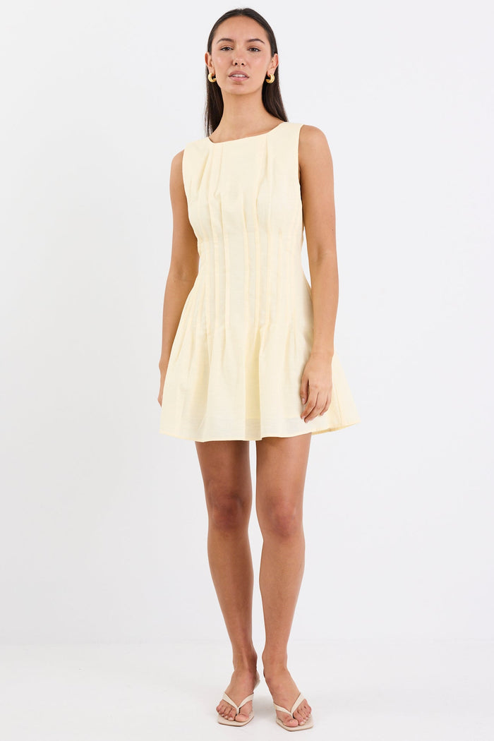 Woman wearing a light yellow sleeveless dress on a white background