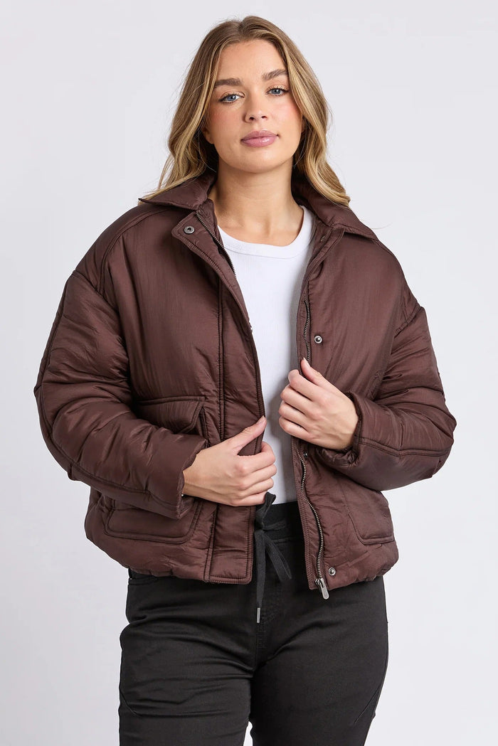 Woman wearing a brown puffer jacket on a white background