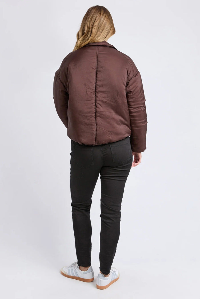 Person wearing a brown puffer jacket and black pants on a white background
col_pattern