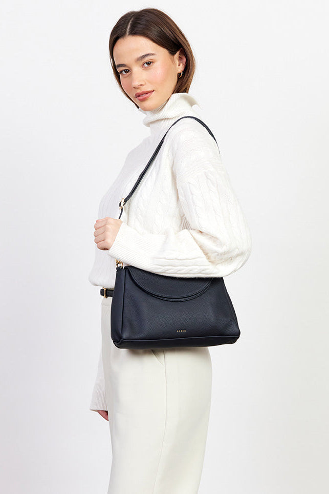 Woman holding a black handbag against a white background