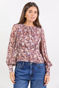 Woman wearing a floral blouse and blue jeans against a white background
