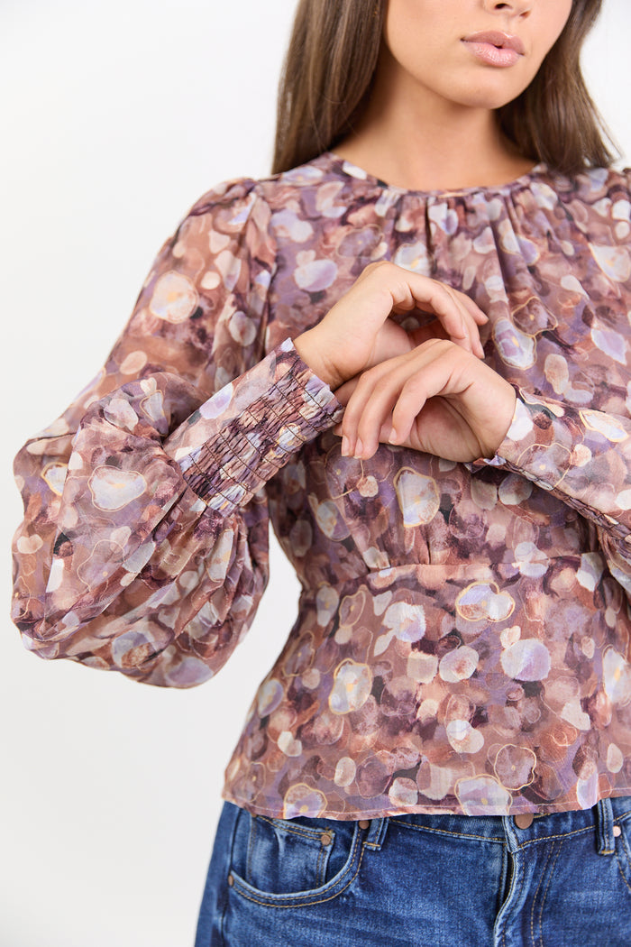 Woman wearing a floral blouse with long sleeves on a white background