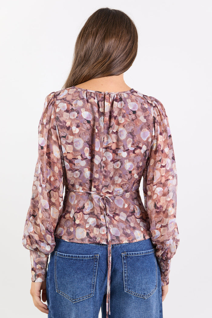 Woman wearing a patterned blouse and blue jeans on a white background
