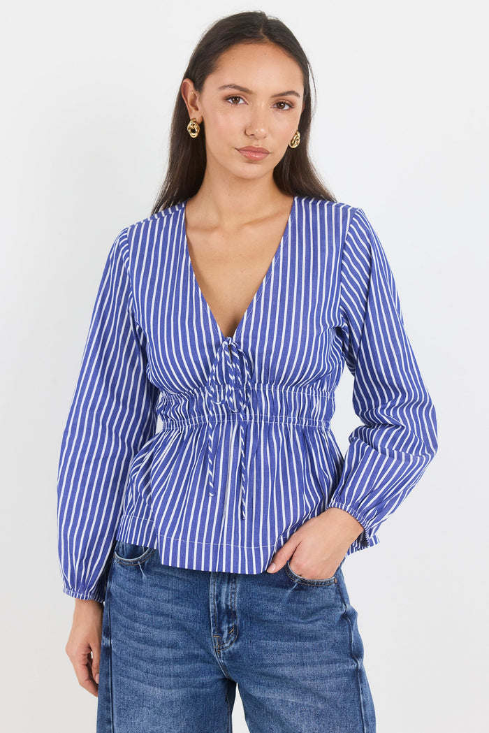 Woman wearing a blue and white striped blouse with long sleeves on a white background