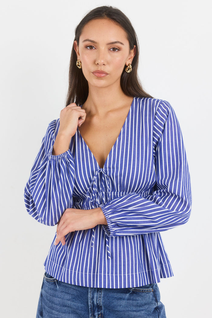Woman wearing a blue and white striped blouse with a plain background