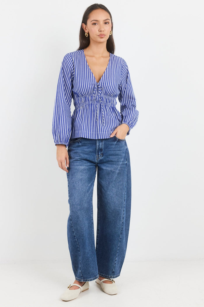 Woman wearing a blue and white striped blouse and blue jeans on a white background