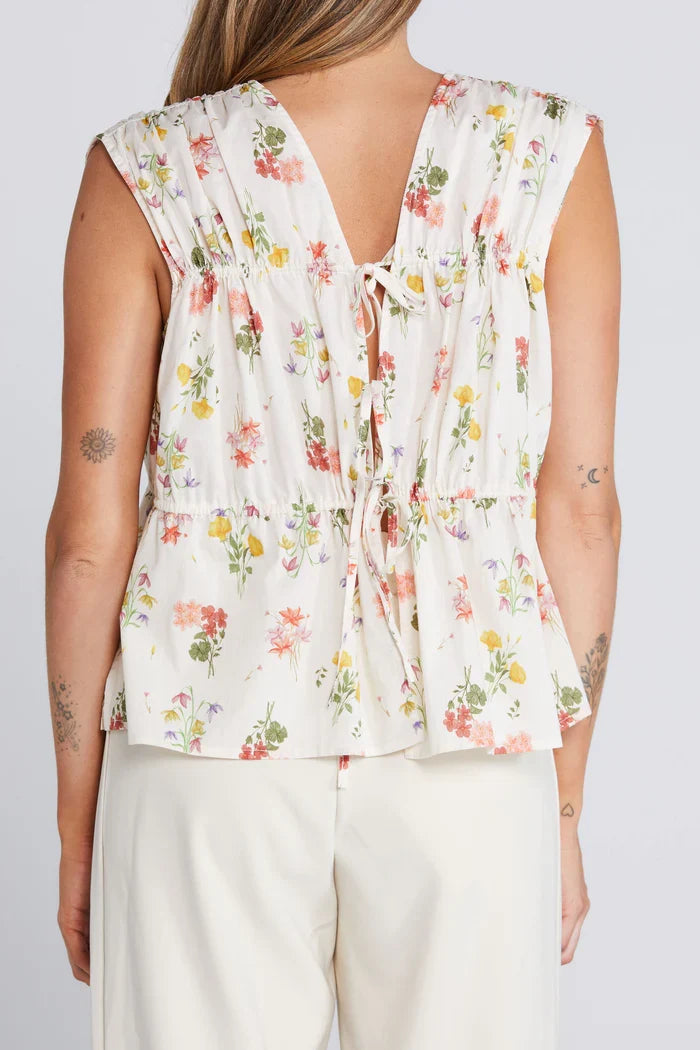 woman wearing a cream floral top and cream pants