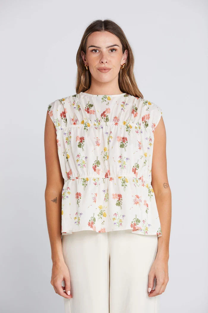woman wearing a cream floral top and cream pants
