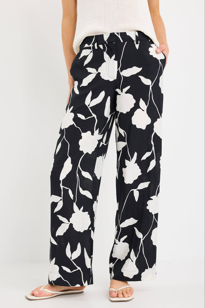 Black pants with white floral pattern worn by a person on a white background