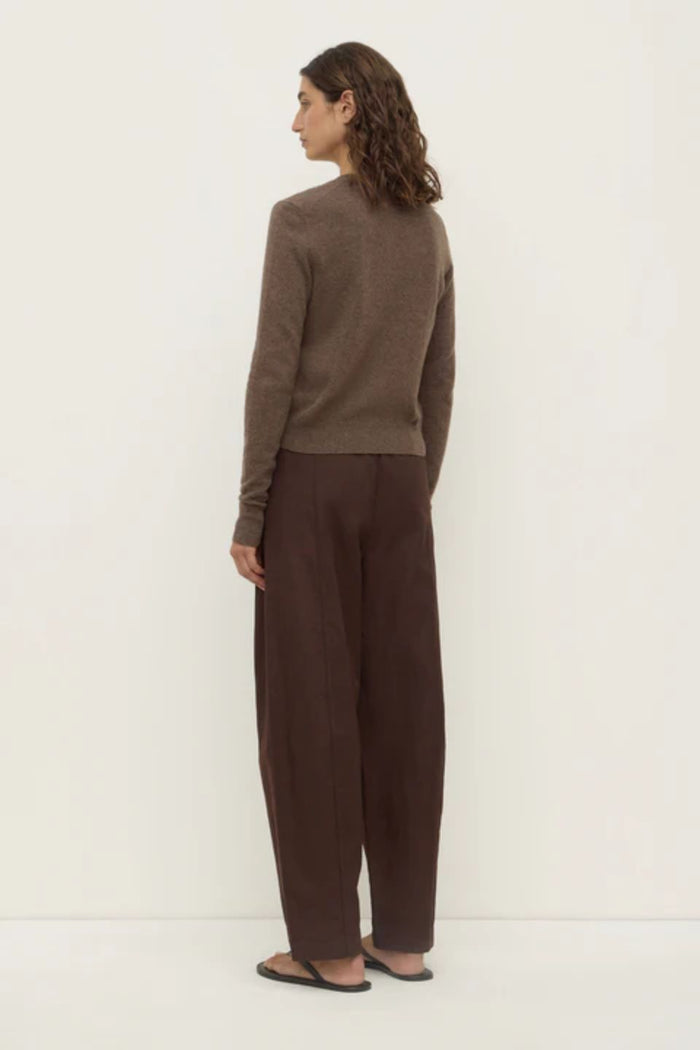 Woman wearing a brown sweater and pants on a white background