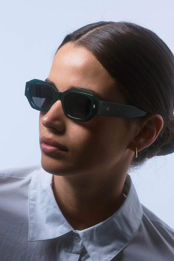 Person wearing dark sunglasses with a plain background