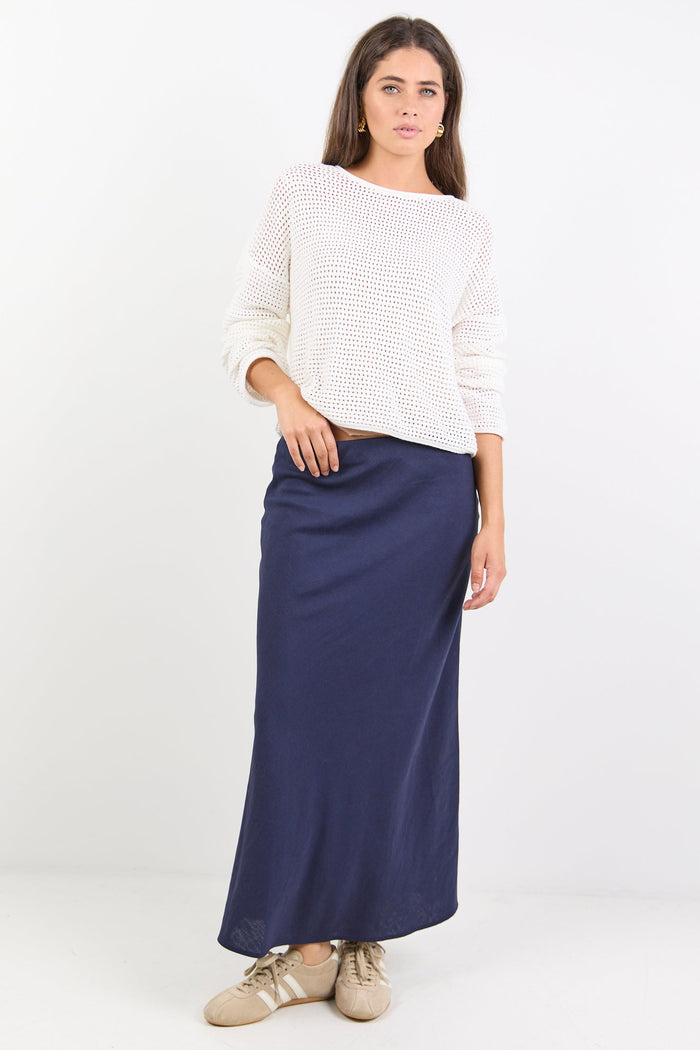 Woman wearing a white sweater and navy skirt on a white background