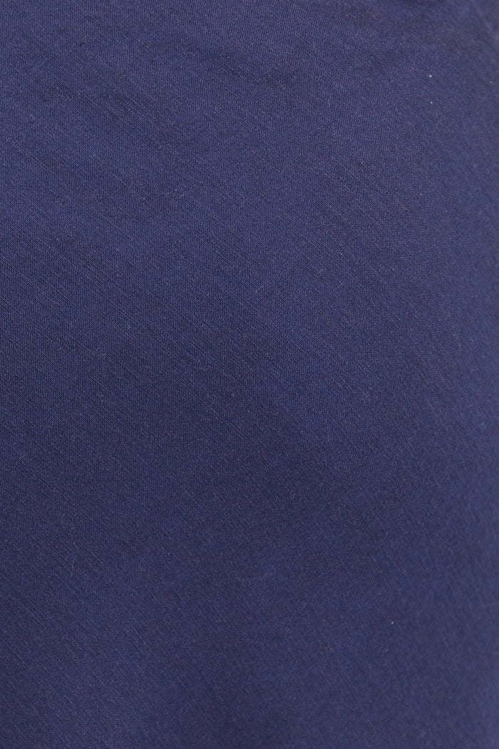 Navy blue skirt worn with a white textured top on a plain background