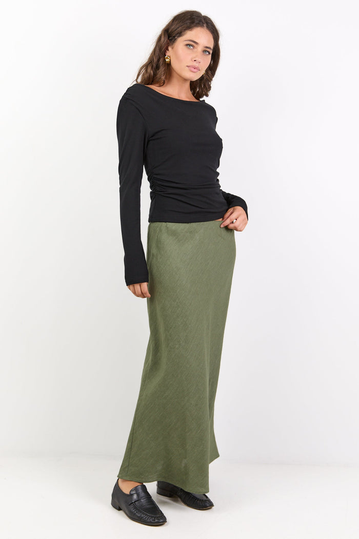 Woman wearing a black long-sleeve top and green skirt on a white background