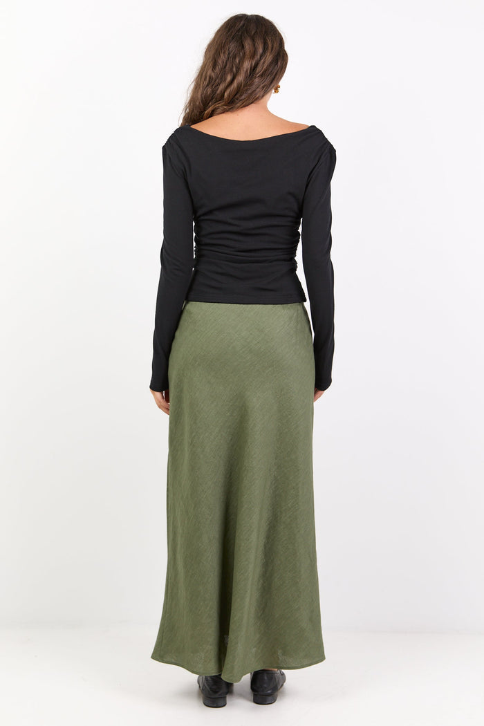 Woman wearing a black long-sleeve top and green skirt on a white background