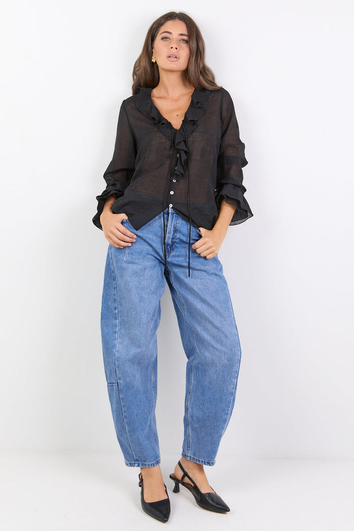 Woman wearing a black blouse and blue jeans on a white background