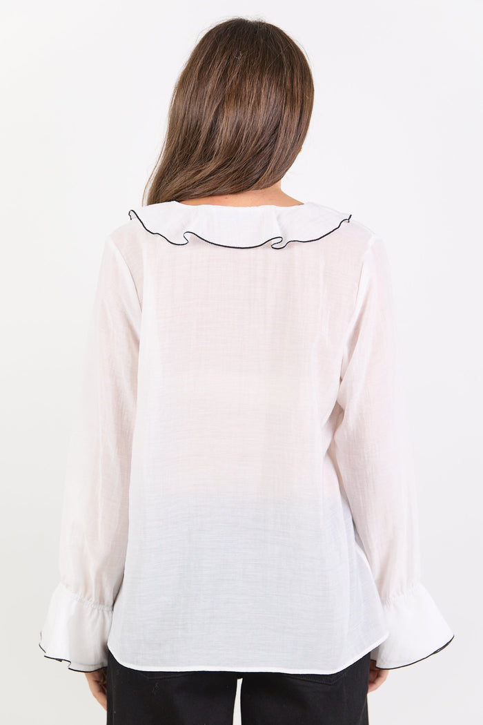 Woman wearing a white blouse with black trim on a white background