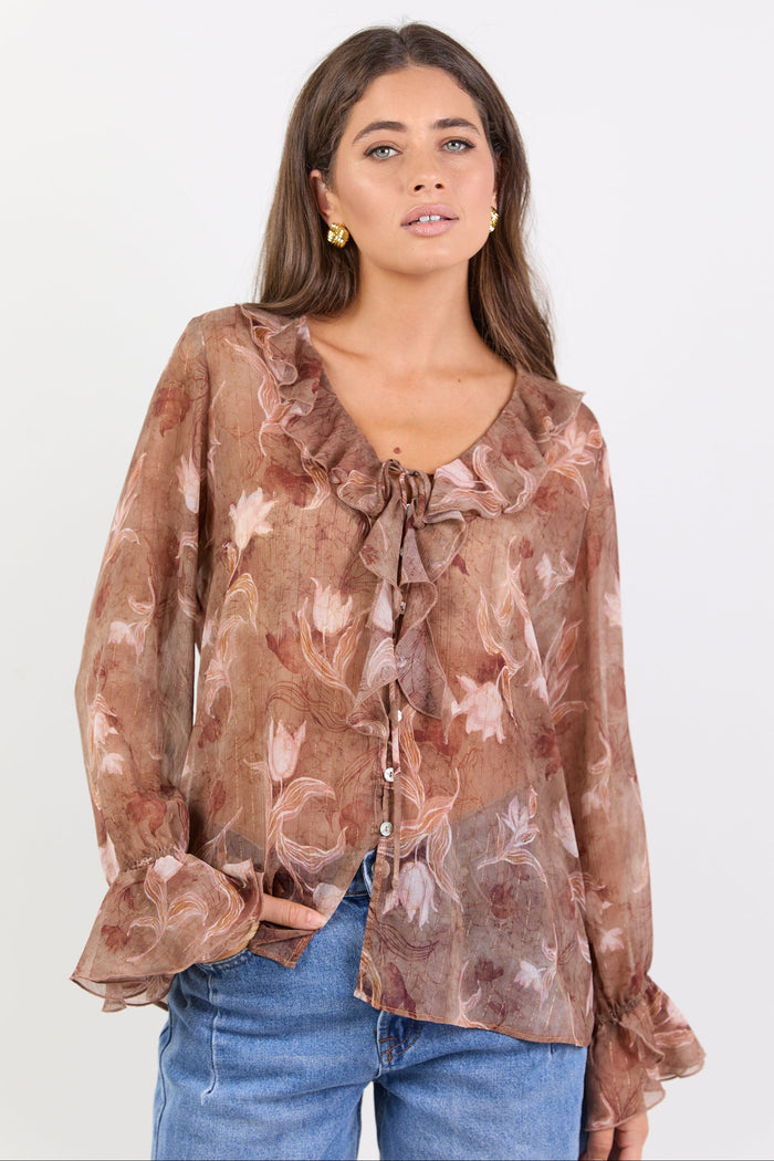 Woman wearing a brown floral blouse with blue jeans on a white background