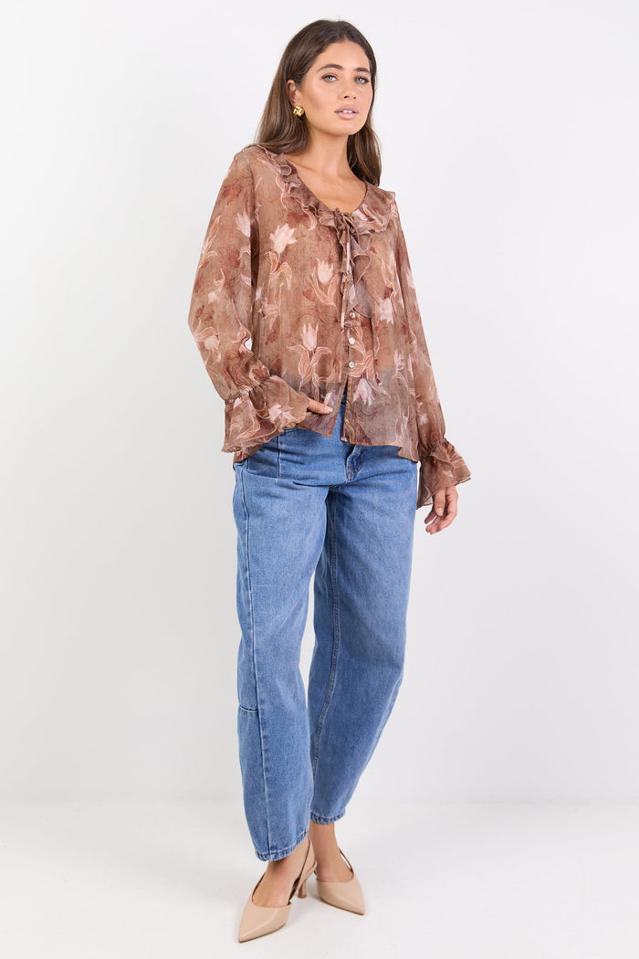 Woman wearing a floral blouse and blue jeans on a white background