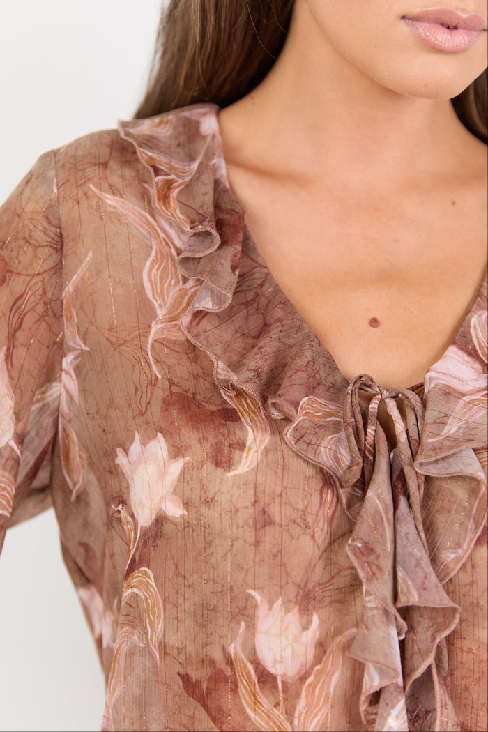 Close-up of a woman wearing a floral blouse with a plain background