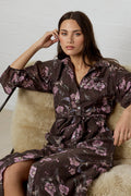 Woman wearing a dark floral dress sitting on a textured chair.
